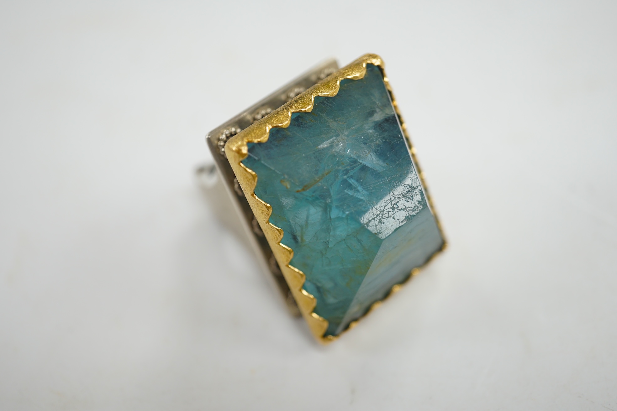 An unusual recent German 925, yellow metal and shaped cut aquamarine set architectural dress ring, the stone weighing approximately 79.00ct, size O/P, gross weight 67 grams. Condition - fair to good